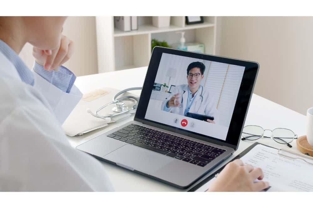  woman staff in labcoat work online remotely talk on phone at office desk in clinic 