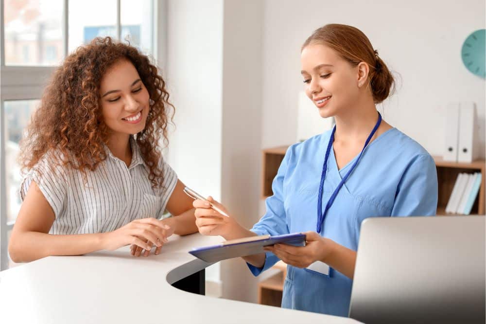 Young female receptionist working with patient in clinic